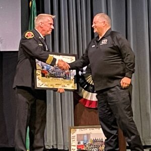 KCDEM representative Michael Robinson receiving a framed picture of the graduating class